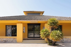 A yellow building with a tiled roof, a reception area, and a staircase leading to the entrance. - Paese Serenu (Porto-Vecchio)