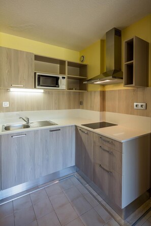 A modern kitchen with built-in appliances, a sink, and wooden cabinetry. - Paese Serenu (Porto-Vecchio)