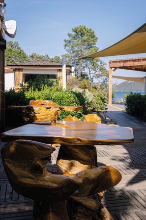 A wooden outdoor table and chairs, a pergola, and a view of the ocean. - Paese Serenu (Porto-Vecchio)