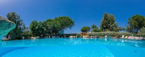 A clear blue swimming pool with lounge chairs and a building in the background. - Paese Serenu (Porto-Vecchio)