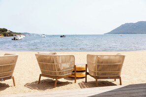 A beach with three wicker chairs and a wooden table, overlooking calm waters and boats. - Paese Serenu (Porto-Vecchio)