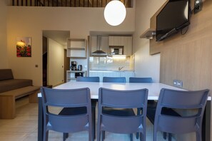 Una cocina moderna con comedor, electrodomésticos integrados y un televisor de pantalla plana en la pared.