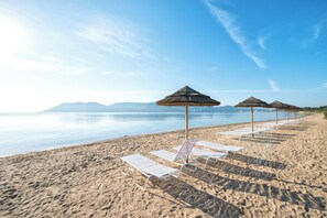 Uma praia com cadeiras de praia brancas e toldos de palha.