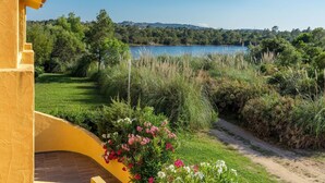 A yellow building with a view of a lake and surrounding greenery. - Paese Serenu (Porto-Vecchio)