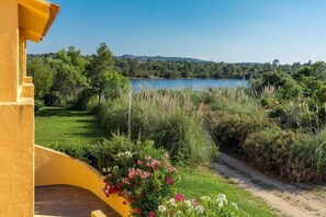 A yellow building with a view of a lake and surrounding greenery. - Paese Serenu (Porto-Vecchio)