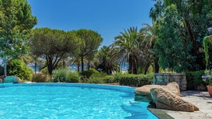 A clear blue swimming pool surrounded by lush greenery and large rocks. - Paese Serenu (Porto-Vecchio)