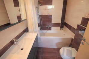 Een badkamer met een bad, wastafel en toilet.