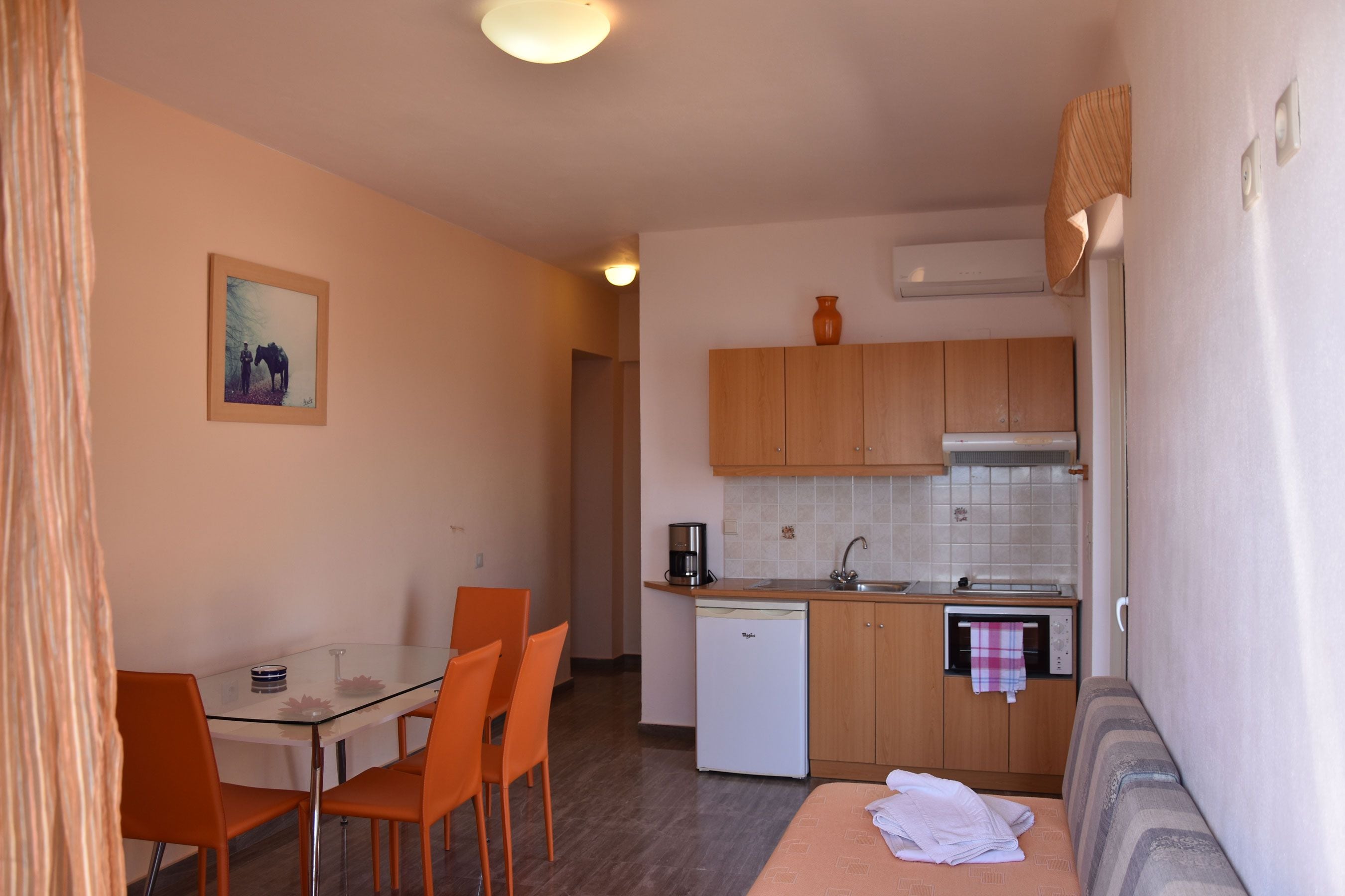 Una cocina compacta con comedor, un refrigerador pequeño y un sofá.