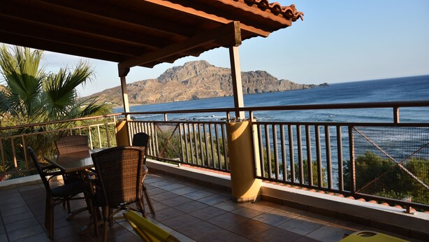 Un espacio de estar techado al aire libre, con vistas al mar y las montañas.