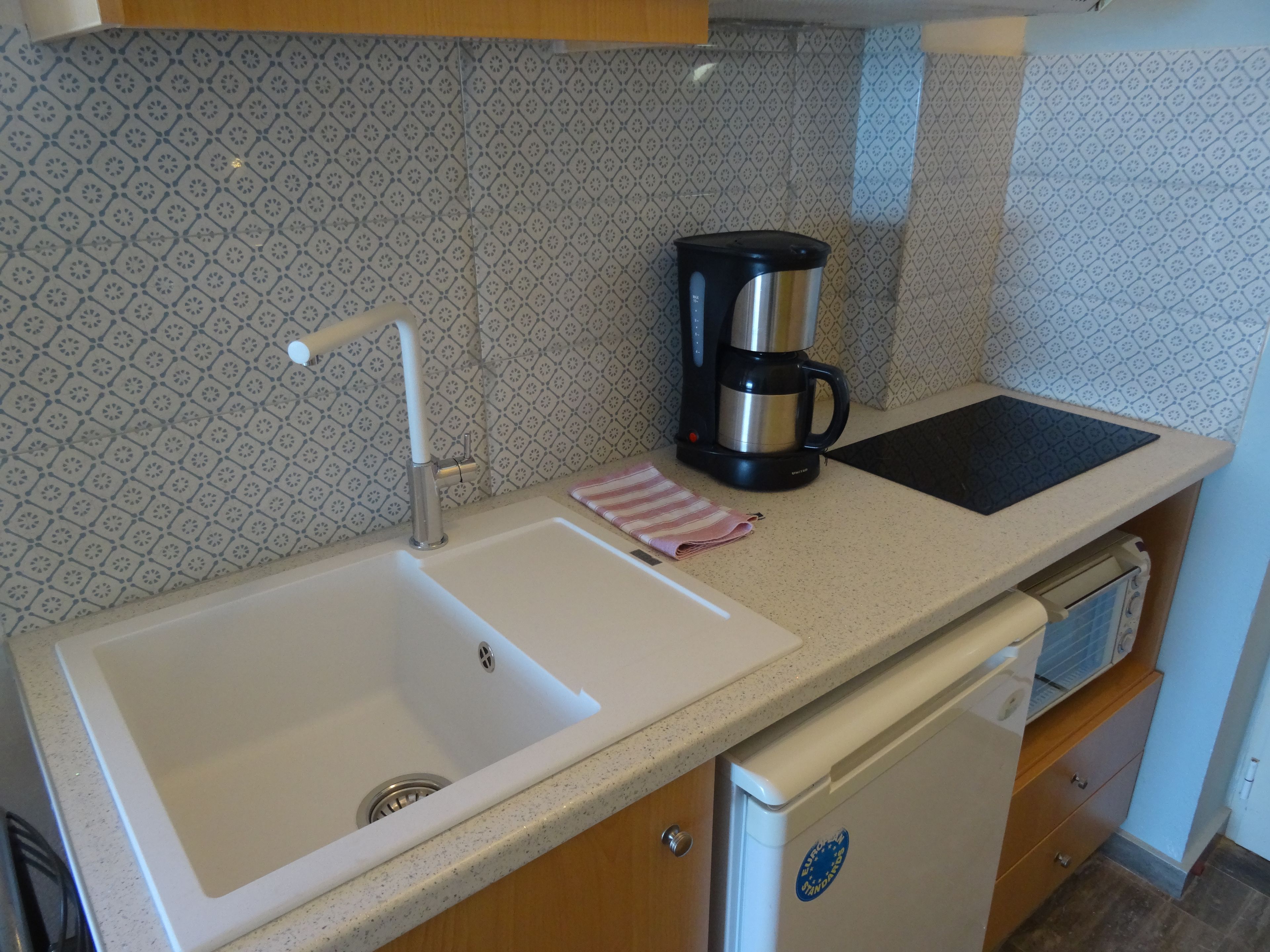A kitchen with a double sink, a coffee maker, and a dishwasher.