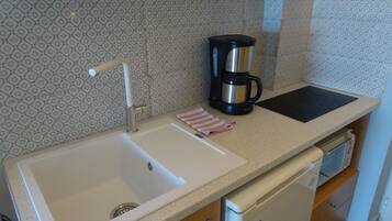 A kitchen with a double sink, a coffee maker, and a dishwasher.