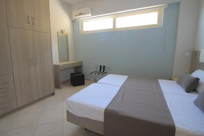 Une chambre à coucher comprenant un lit, une armoire, un miroir, un appareil de climatisation et une fenêtre.