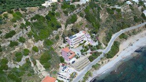 Vista aérea de una propiedad costera con varias construcciones, un camino y una playa.