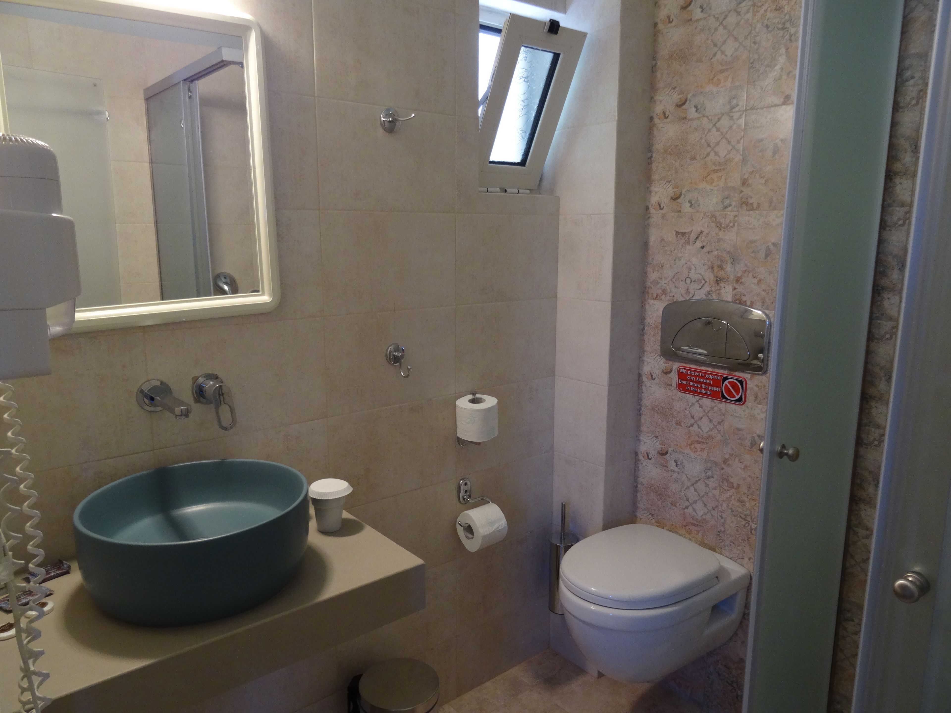 Un baño con lavamanos, inodoro y espejo.
