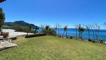 A grassy outdoor area with a view of the sea and mountains in the background.