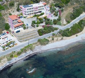 Luchtbeeld van een kusthotel met meerdere gebouwen, een strand en een helder uitzicht op zee.