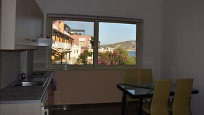 Una cocina con ventana, una mesa de comedor con sillas y vistas a edificios y colinas.