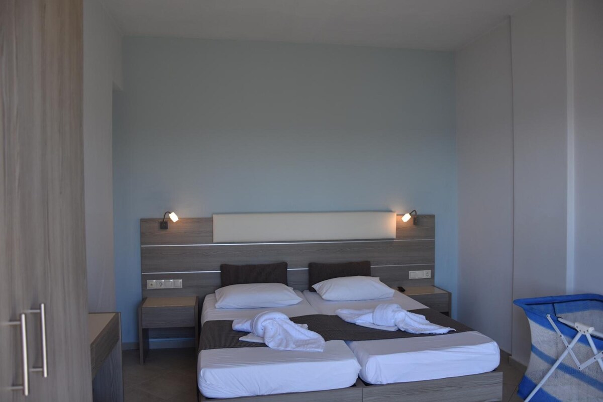 Een hotelkamer met een bed, nachtkastjes en een wandlamp.