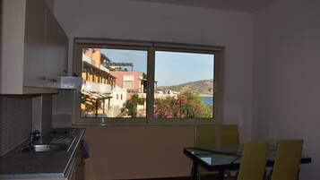 Una cocina con ventana, una mesa de comedor con sillas y vistas a edificios y colinas.