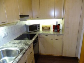 Kompakti keittiö, jossa on mikroaaltouuni, leivänpaahdin ja astianpesukone.