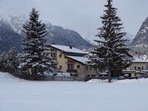 A two-story building with a sloped roof, surrounded by snow-covered trees and mountains. - Arsura, (Zernez) by Interhome (Zernez)