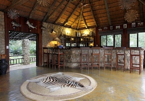 A rustic interior with a stone wall, wooden bar, and a zebra rug. - Shayamoya Tiger Fishing & Game Lodge (Pongola)