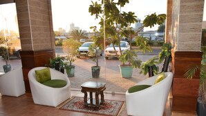 A lobby with two white armchairs, a small table, and potted plants. - Arinza Tower Quality Suites (Salmiya)