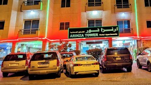 A multi-story hotel with illuminated balconies and a sign indicating it is the Arinza Tower Hotel. - Arinza Tower Quality Suites (Salmiya)