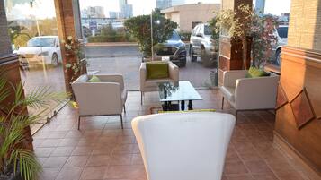 A terrace with outdoor seating, a view of the city, and a building with a brick facade.