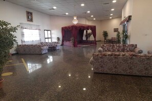 A spacious lobby with patterned sofas, a red canopy stage, and a chandelier.
