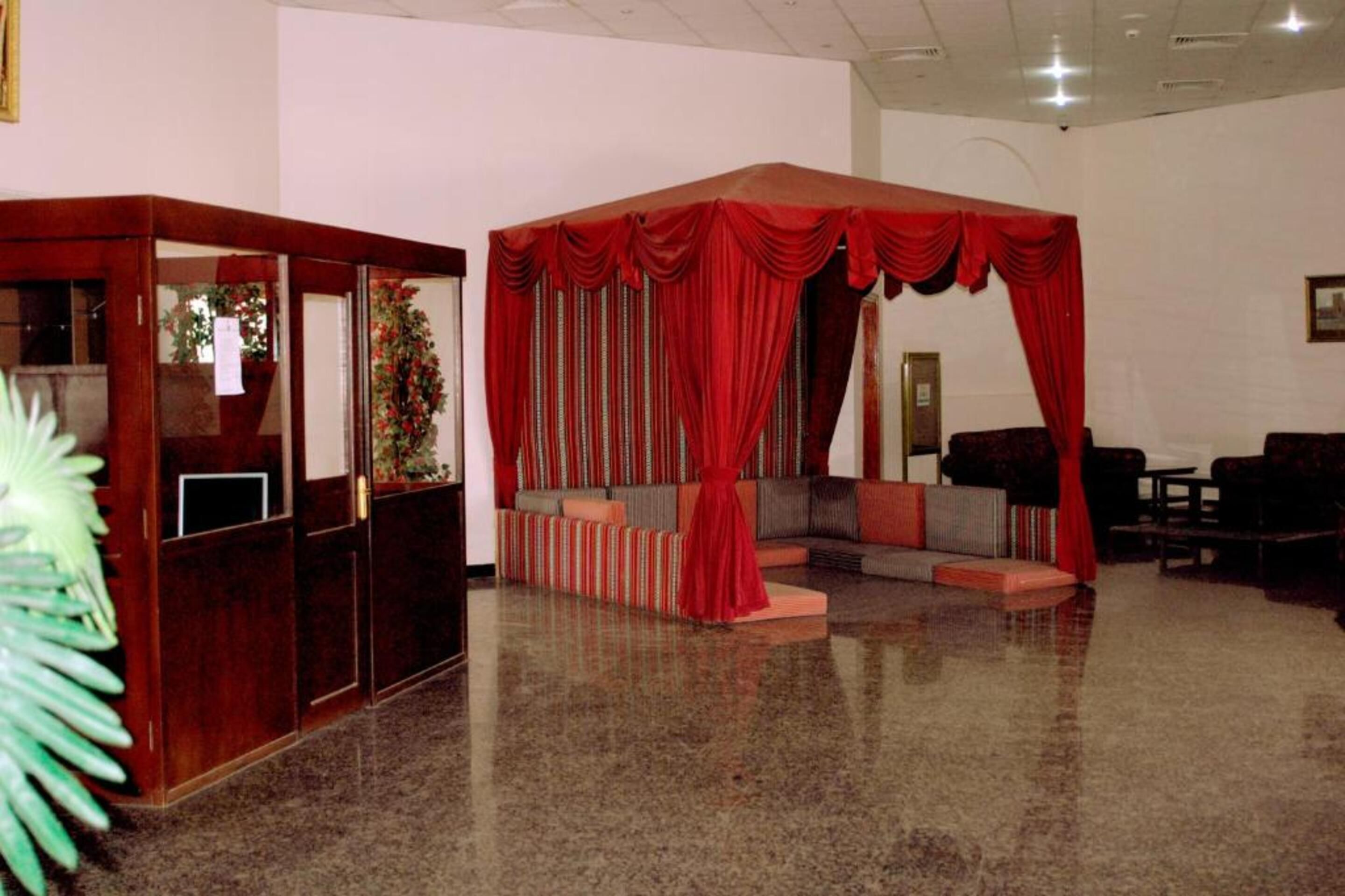 A lobby with a seating area, a reception desk, and a large red curtain.