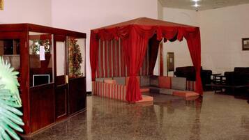 A lobby with a seating area, a reception desk, and a large red curtain.