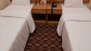 A hotel room with two single beds, a wooden nightstand between them, a tissue box, and a phone charger. - OYO 142 Al Sharqiya Sands Hotel (Ibra)