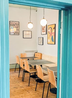 A dining area with a table and chairs, a sofa, and wall art. - Selina St Kilda Melbourne (Melbourne)