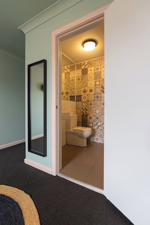 A room with a door leading to a bathroom with patterned tiles and a toilet. - Selina St Kilda Melbourne (Melbourne)
