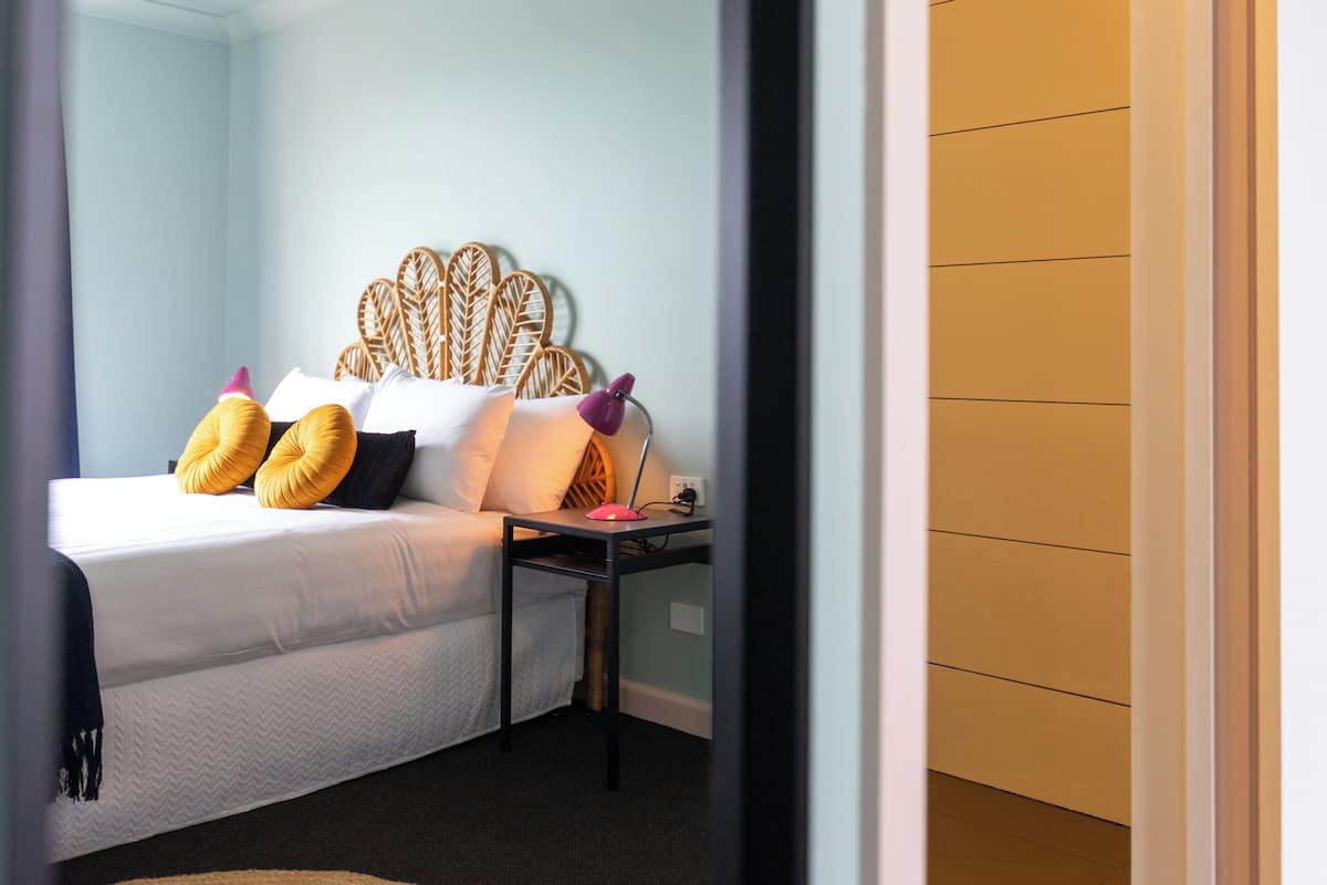 A bed with a white comforter, two yellow pillows, and a wooden headboard.