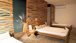 A room with two wooden beds, a woven partition, and a small round table with a vase. - Veranda Tamarin Hotel & Spa (Tamarin)