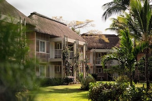 Un hotel con edificios de techo de paja, un jardín bien cuidado y un cielo despejado.