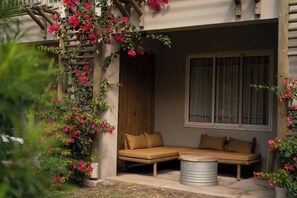 A room with a sofa, a window, and a wooden structure with flowers. - Veranda Tamarin Hotel & Spa (Tamarin)