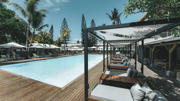 A poolside area with lounge chairs, a wooden deck, and a covered seating area.