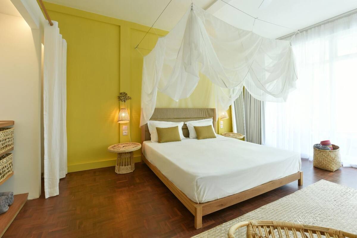 A bedroom with a bed, bedside tables, a lamp, and a window with curtains.