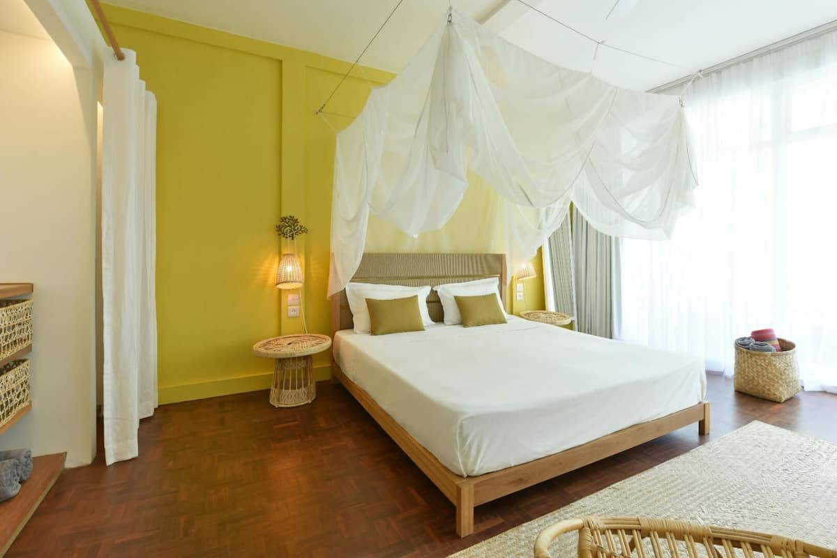 A bedroom with a bed, bedside tables, a lamp, and a window with curtains.