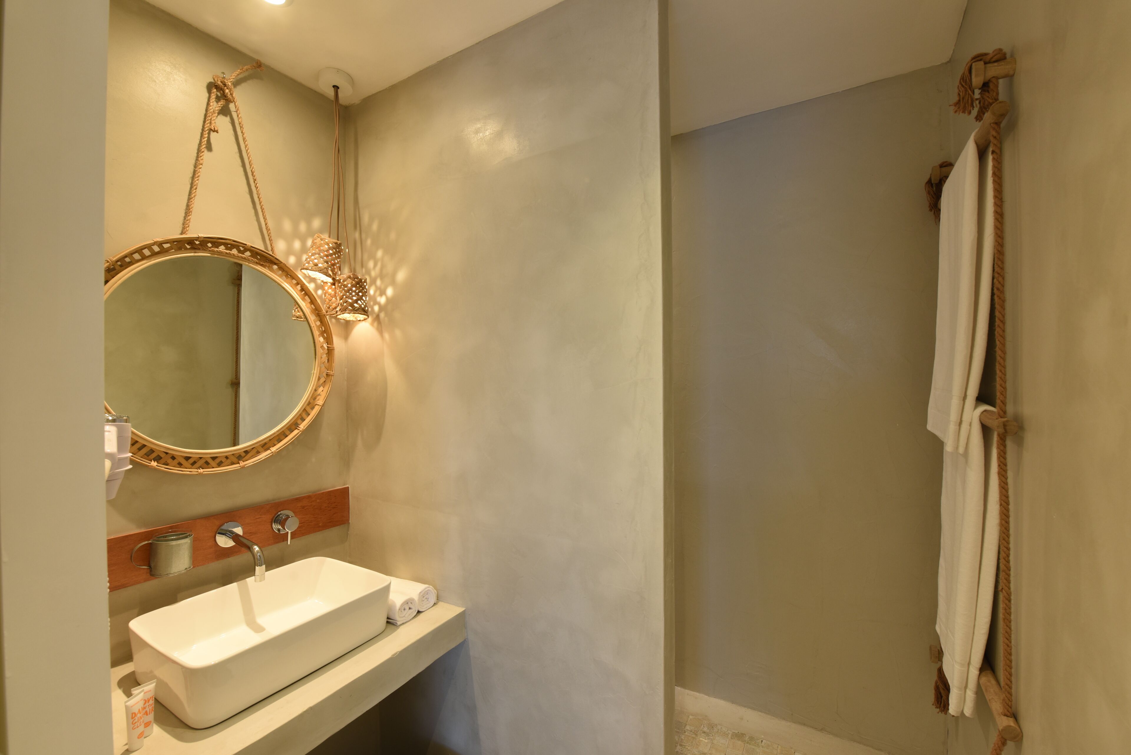 A bathroom with a white sink, a round mirror with a wooden frame, a towel rack, and a shower curtain.