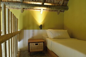 A small, single-bed room with a wooden headboard, a nightstand, a wall-mounted light, and a woven basket. - Veranda Tamarin Hotel & Spa (Tamarin)