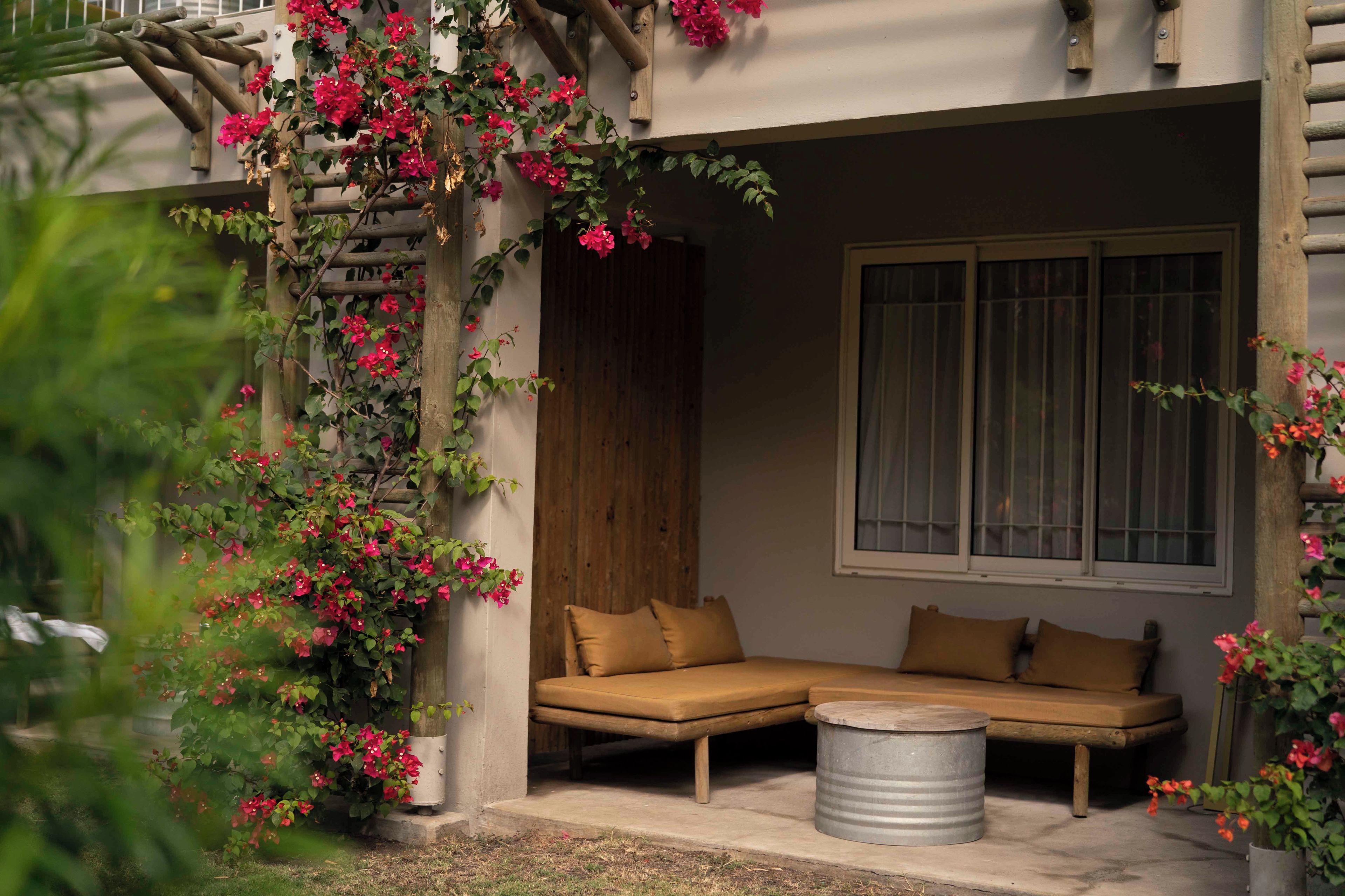 A room with a sofa, a window, and a wooden structure with flowers.