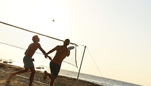 Duas pessoas jogando voleibol de praia perto de uma rede.