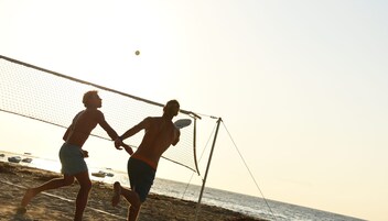 Dos personas jugando voleibol de playa cerca de una red.