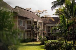 A resort with thatched-roof buildings, a well-maintained lawn, and tropical vegetation. - Veranda Tamarin Hotel & Spa (Tamarin)