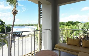 A balcony with a view of a beach and palm trees.