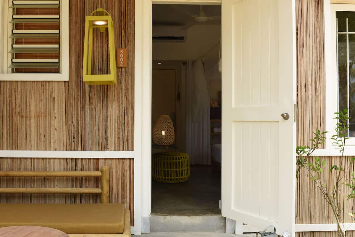 A wooden exterior with a bench, a door, and a window with blinds.